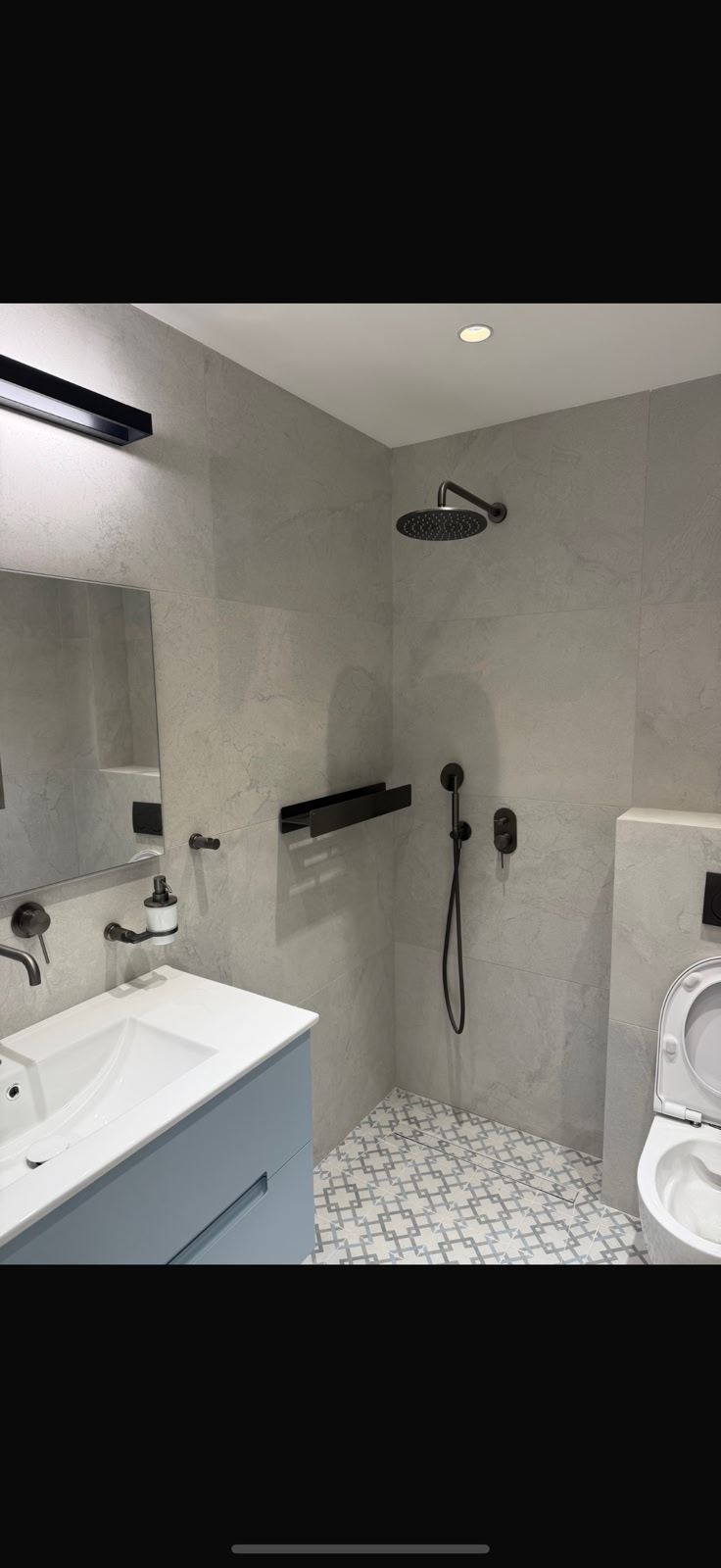 חדר רחצה מודרני ומואר בגוון אפור עם מקלחת גשם — שיפוץ של א.א שיפוצים ועבודות גמר